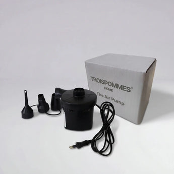 Black air pump with attachments and a gray box labeled 'TROISPOMIMES' on a white background
