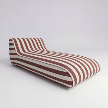 Striped lounge chair with red and white pattern on a light gray background