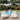 Woman arranging beige outdoor sun bed loungers by a swimming pool in a garden - TROISPOMMES HOME