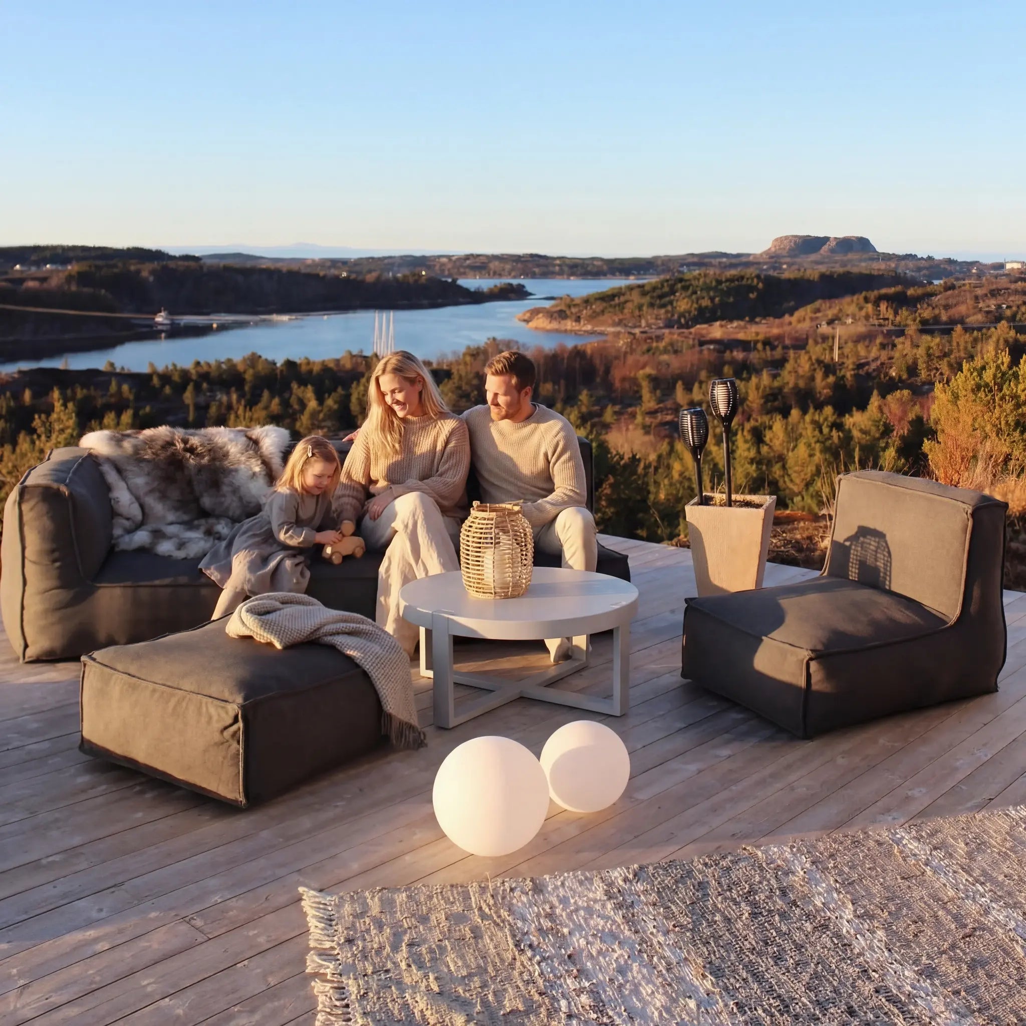 Family relaxing on Troispommes outdoor furniture on patio with lake view