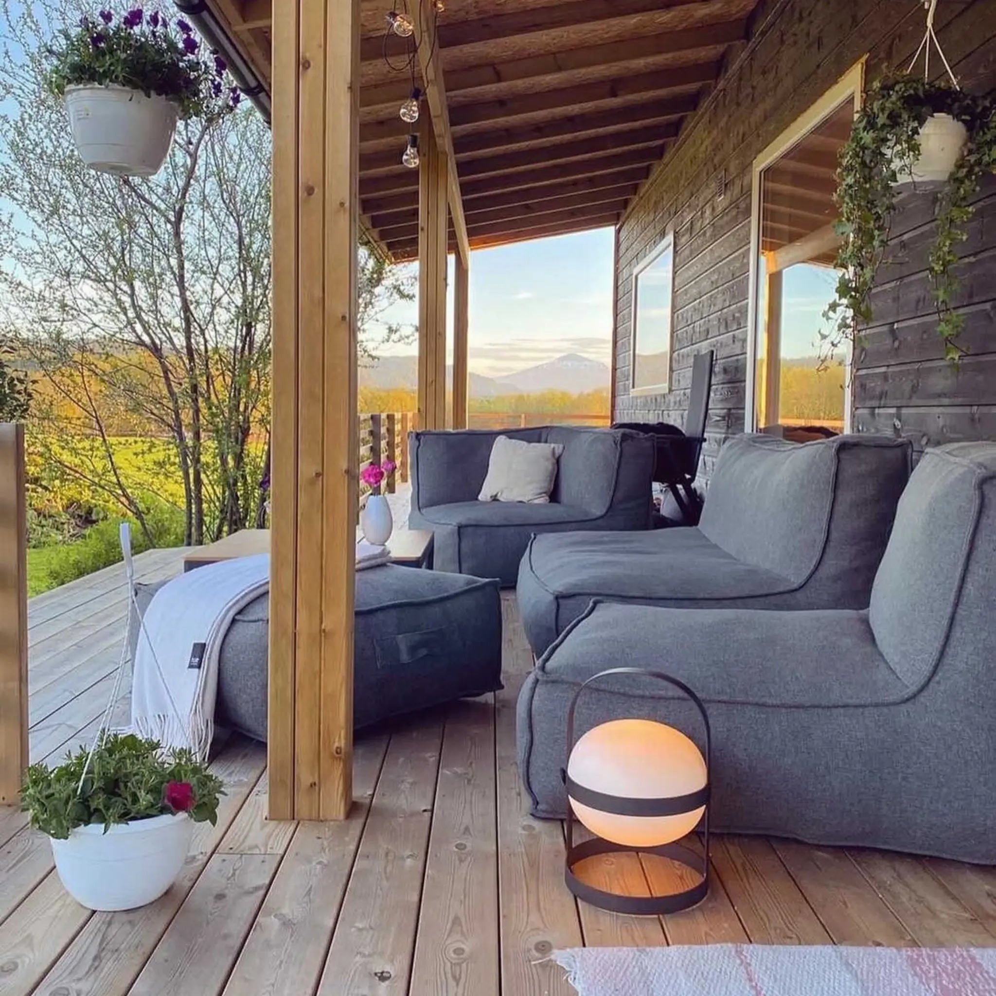 Dark Grey outdoor lounge set on a cozy wooden cabin terrace with mountain view at sunset - TROISPOMMES HOME